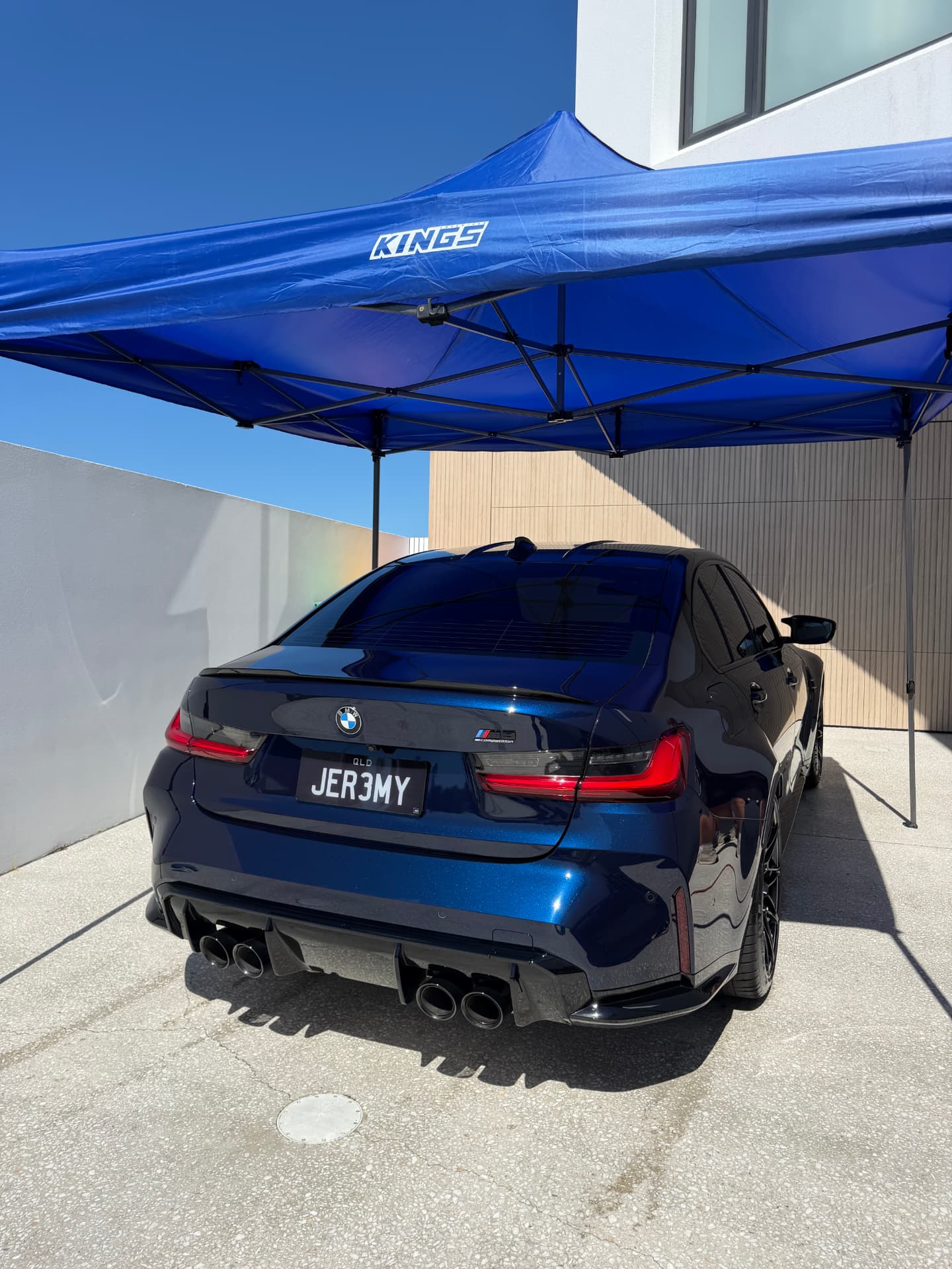 Metallic blue BMW M3 finished with a mirror shine under a mobile detail bay
